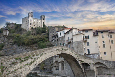 Castle and buildings in town against cloudy sky