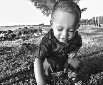 Cute boy crouching on field