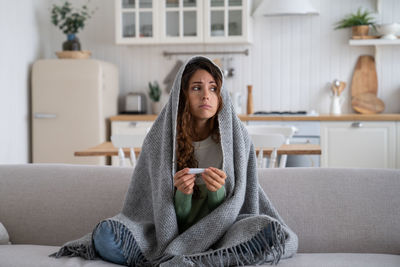 Young woman sitting on sofa at home