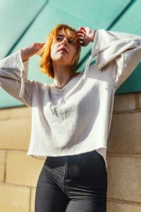 Portrait of young woman standing against wall