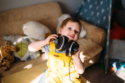 Funny little child having fun with headphones at home, portrait.