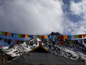 Multi colored flags on snowcapped mountain against sky