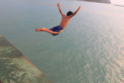 Full length of shirtless man jumping in water