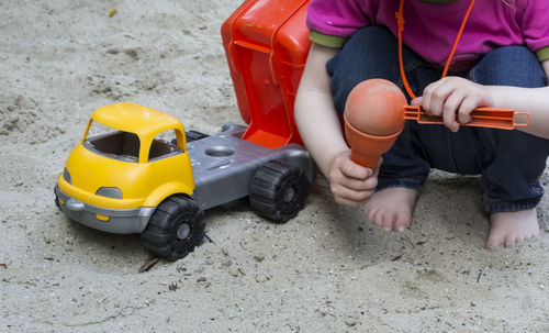 Low section of boy playing with toy car at beach