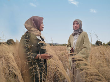 Twi young woman standing on field against sky