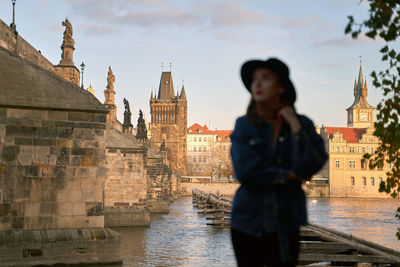 Side view of young woman standing against building