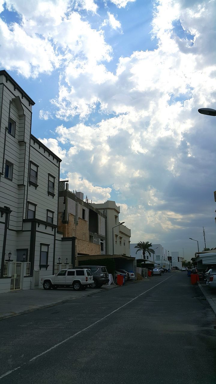 transportation, car, land vehicle, mode of transport, building exterior, road, sky, street, architecture, built structure, cloud - sky, road marking, the way forward, city, cloudy, cloud, city street, diminishing perspective, stationary, parking