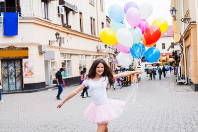 Woman with balloons at street in city