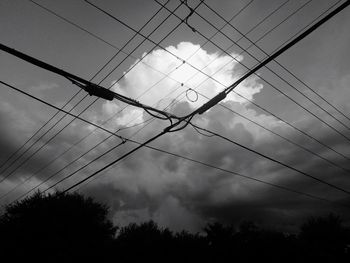 Low angle view of electricity pylon against cloudy sky