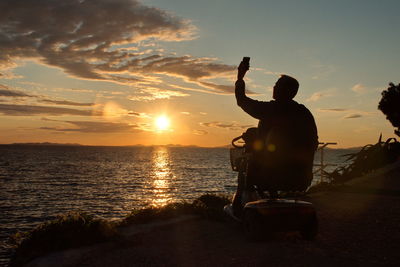 Silhouette man on beach against sky during sunset