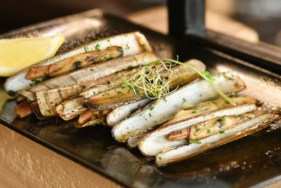 The shells knives, parsley and half a lemon on black plate