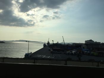 Silhouette of harbor against cloudy sky