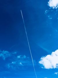 Low angle view of vapor trails against blue sky