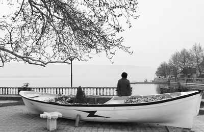 Rear view of man in boat on lake against sky