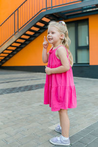 Portrait of young woman standing on footpath