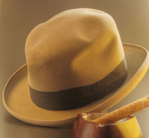 Close-up of cigar with hat against brown background