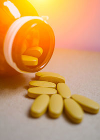 Close-up of yellow pills and bottle on table