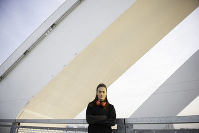 Portrait of young woman sitting on railing against wall