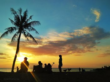 Silhouette people on beach against sky during sunset