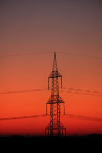 Low angle view of silhouette electricity pylon against romantic sky