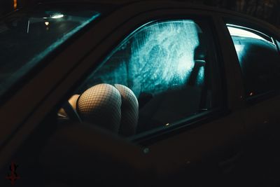 Midsection of seductive woman in car seen through window at night