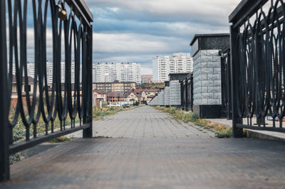 Footpath amidst buildings in city against sky