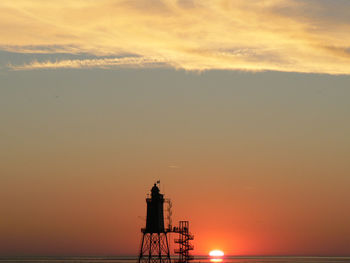 Silhouette lighthouse against sky during sunset