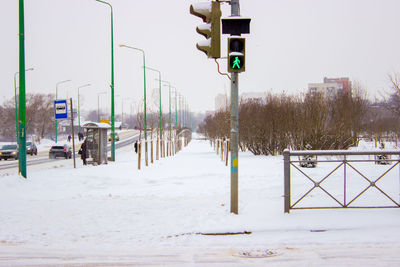 Road signs on snow covered field against sky