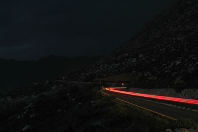 Light trails on road against sky at night