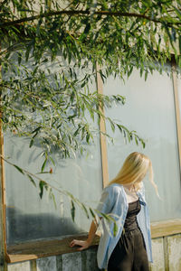 Rear view of woman with umbrella against trees