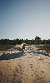 Man riding motorcycle on beach against clear sky