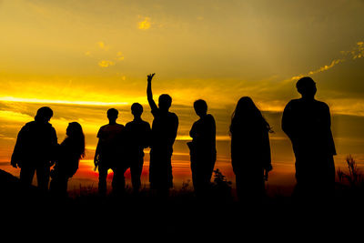 Silhouette people standing on beach against sky during sunset