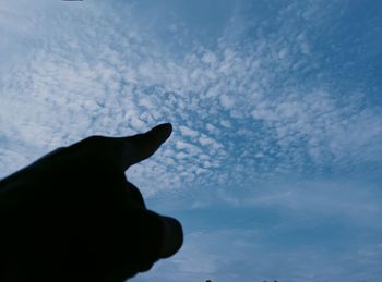 Low angle view of silhouette hand against sky