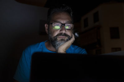 Man using laptop sitting in darkroom