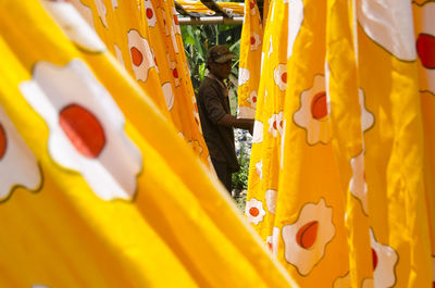 Side view of worker standing amidst textile 