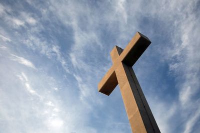 Low angle view of cross by building against sky