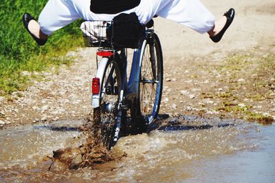 Low section of man riding bicycle on puddle 