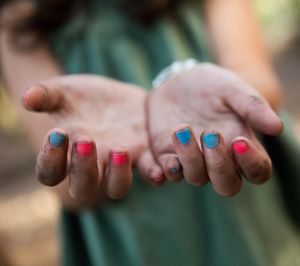 Midsection of woman showing dirty hands with red and blue nail polish