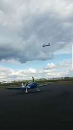 Airplane flying over airport runway against sky