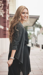 Portrait of smiling beautiful woman walking on footpath