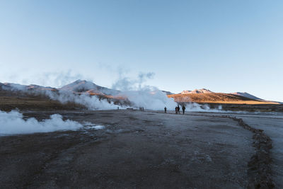 People walking by hot spring against blue sky