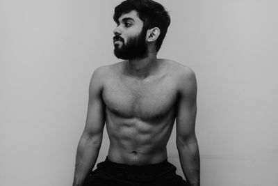 Portrait of young man looking away against white background