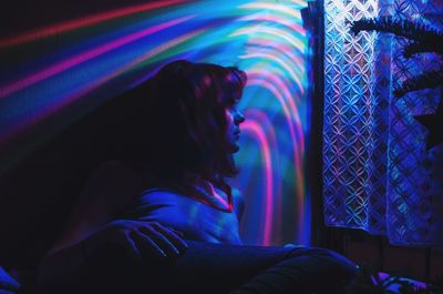 Close-up of young woman sitting on multi colored light