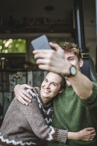 Smiling man taking selfie with woman from mobile phone during camping