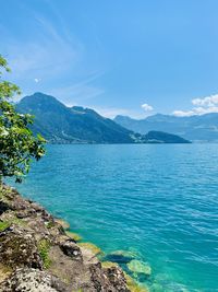 Scenic view of sea and mountains against blue sky