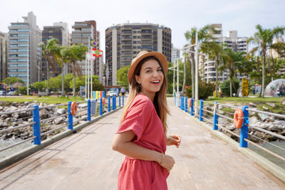 Portrait of smiling relaxed fashion woman walking on florianopolis seafront, santa catarina, brazil