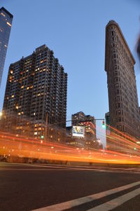 Light trails on road against buildings in city at night