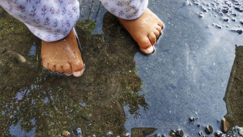 Low section of person standing on wet mud