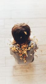 High angle view of man with dry flowers sitting on hardwood floor