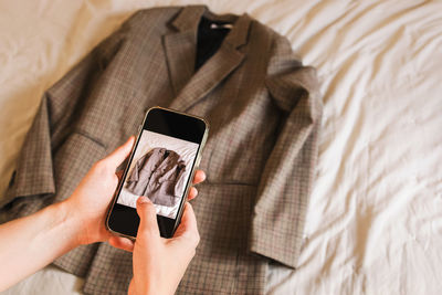 Close-up of woman's hands taking picture of the jacket. selling used clothes online